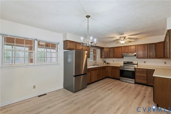 a kitchen with granite countertop a refrigerator and wooden floor