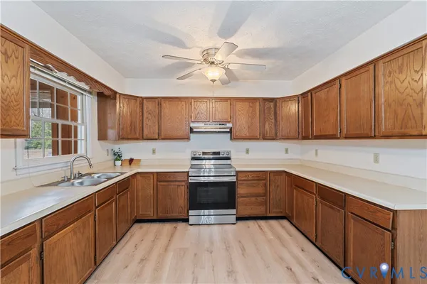 a kitchen with stainless steel appliances granite countertop wooden cabinets a sink a stove a refrigerator and island with wooden cabinets