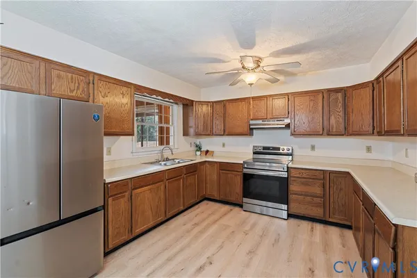 a kitchen with stainless steel appliances granite countertop a stove top oven a refrigerator a sink and dishwasher with wooden cabinets