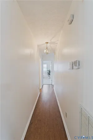 a view of a hallway with wooden floor and a bathroom