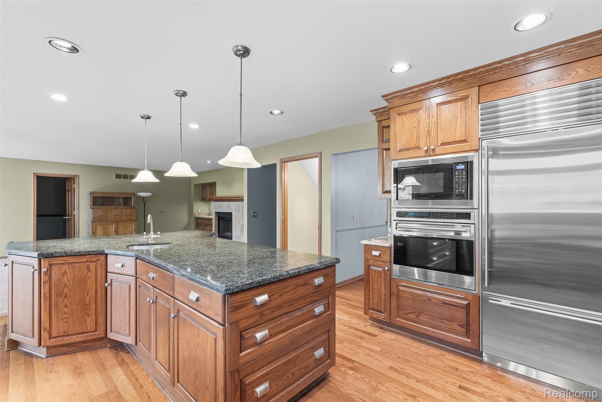 8135 Ranch Estates Road Clarkston, MI 48348 - Photo 10 of 53 Kitchen featuring wood cabinetry, stainless steel appliances, a center island with a sink, and pendant lighting