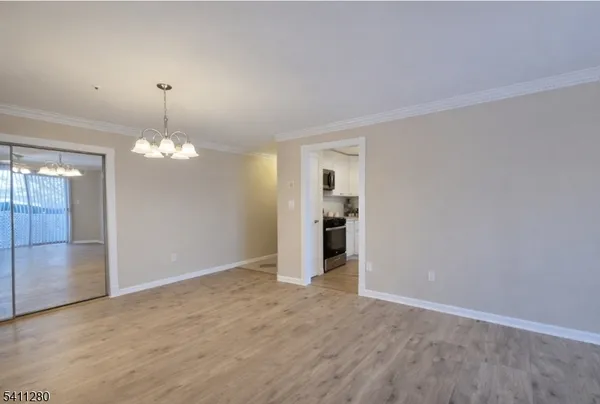 an empty room with kitchen and chandelier fan