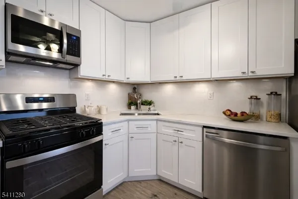a kitchen with white cabinets and black appliances