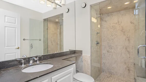a bathroom with a granite countertop sink toilet a shower and a mirror