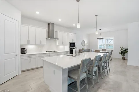 a kitchen with kitchen island a dining table chairs and white cabinets