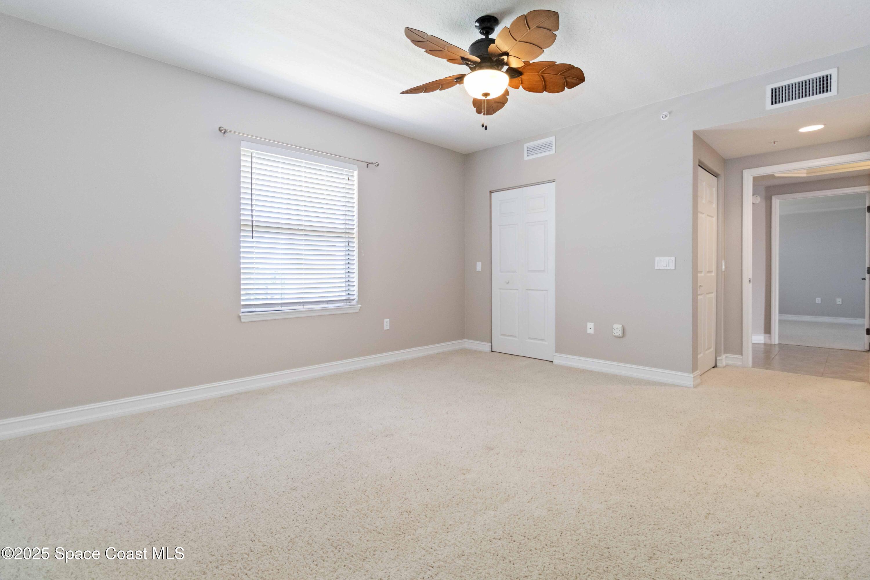 134 Starboard Lane, Unit 404 Merritt Island, FL 32953 - Photo 16 of 30 an empty room with windows and fan chandelier fan