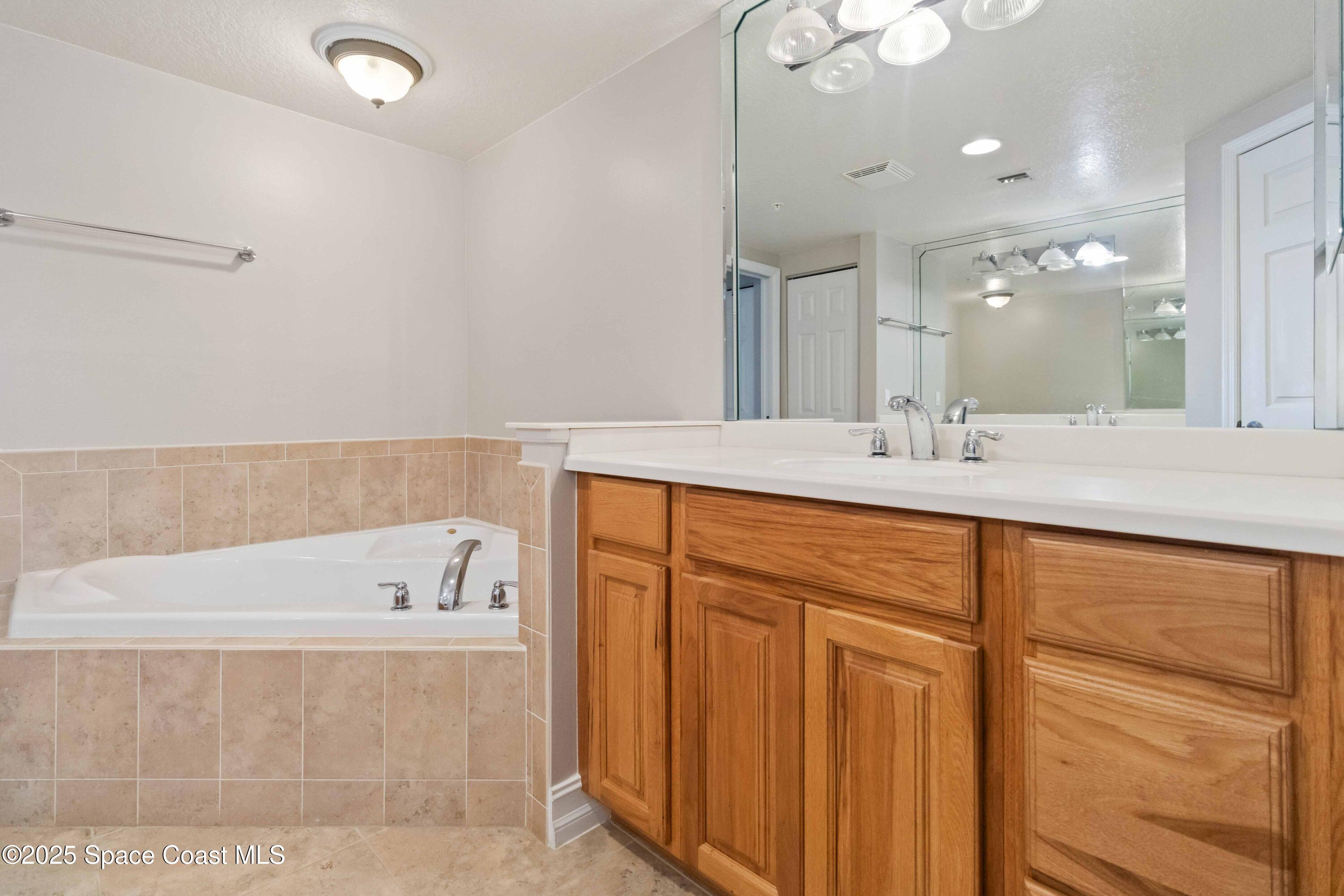 134 Starboard Lane, Unit 404 Merritt Island, FL 32953 - Photo 20 of 30 a bathroom with a tub sink and mirror