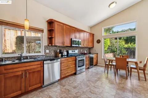 a large kitchen with stainless steel appliances furniture a refrigerator a stove a dining table and chairs