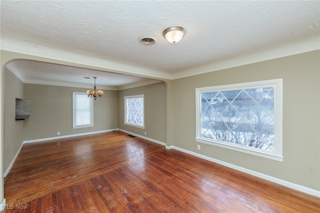 5062 Lee Road Maple Heights, OH 44137 - Photo 4 of 50 Empty room with hardwood / wood-style floors, ornamental molding, a chandelier, and a textured ceiling
