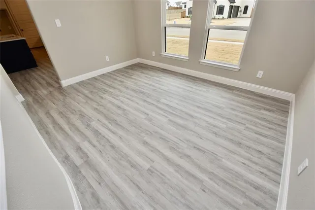 a view of empty room with window and wooden floor