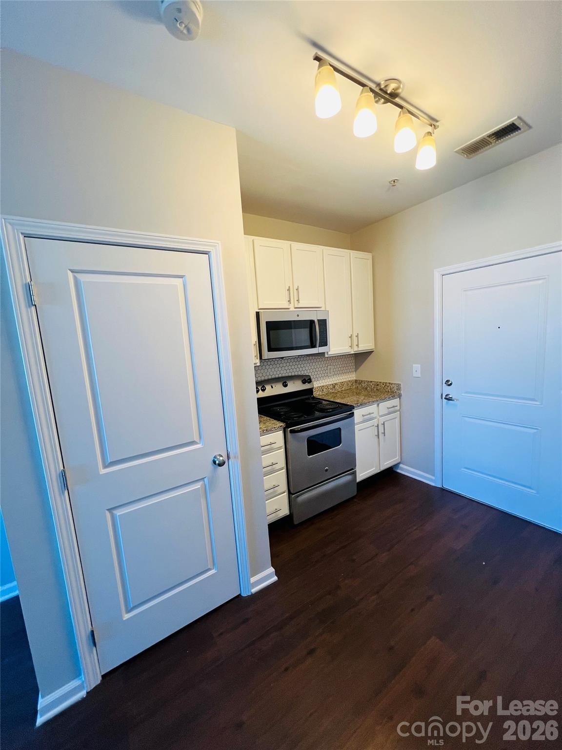 4310 Park Road, Unit 207 Charlotte, NC 28209 - Photo 3 of 9 a kitchen with a refrigerator a stove top oven and wooden floor