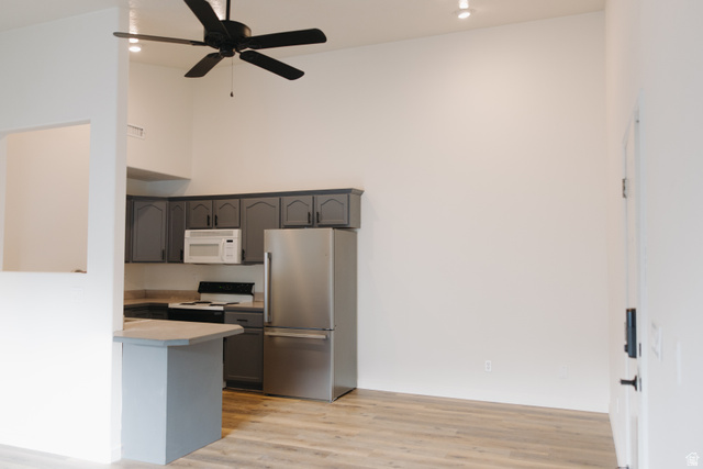 215 South 1050th West, Unit 10 Provo, UT 84601 - Photo 5 of 38 Kitchen featuring freestanding refrigerator, a high ceiling, light countertops, white microwave, and light wood-type flooring