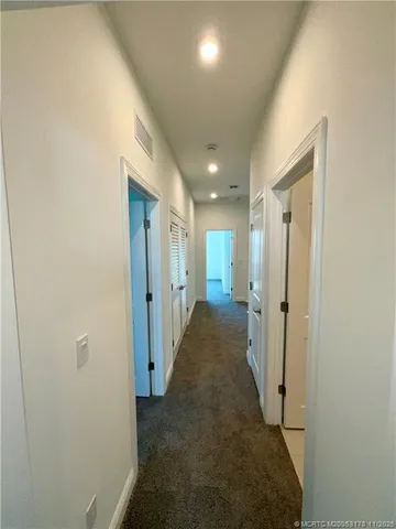 a view of a hallway with wooden floor and a bathroom