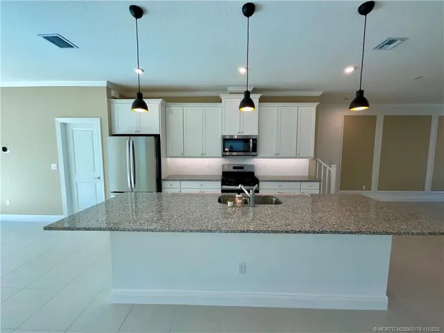 a kitchen with stainless steel appliances granite countertop a sink a counter top space cabinets and wooden floor