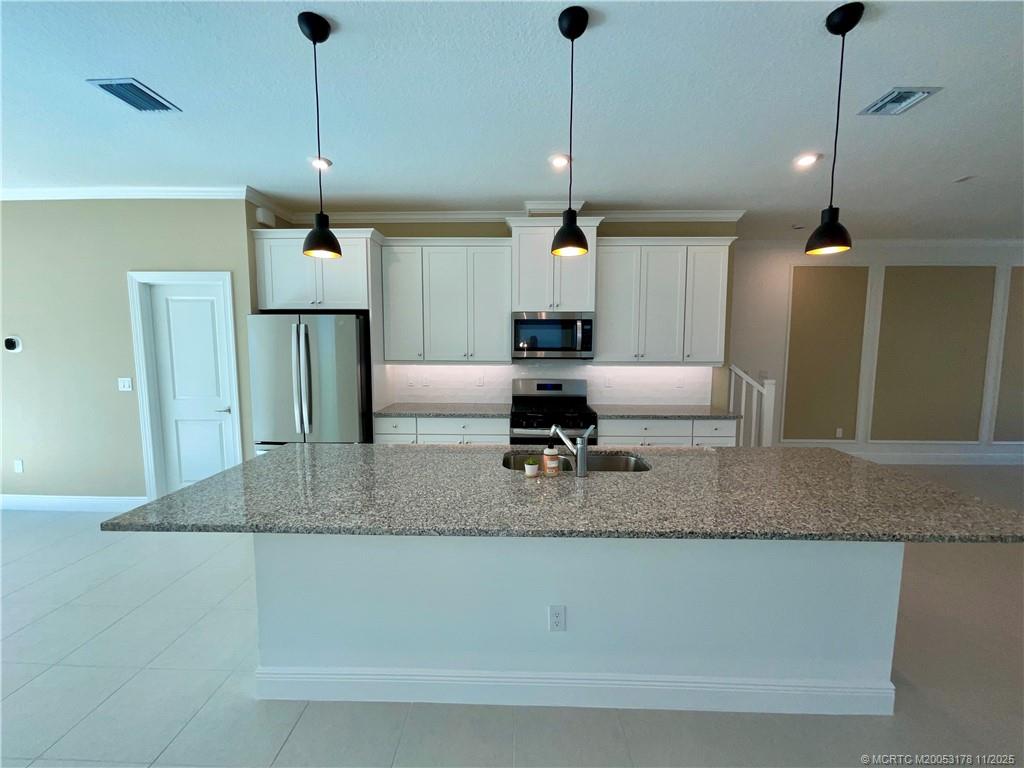 860 Southwest Bushel Trail Palm City, FL 34990 - Photo 4 of 25 a kitchen with stainless steel appliances granite countertop a sink a counter top space cabinets and wooden floor