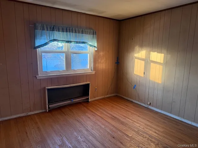 an empty room with wooden floor cabinet and windows