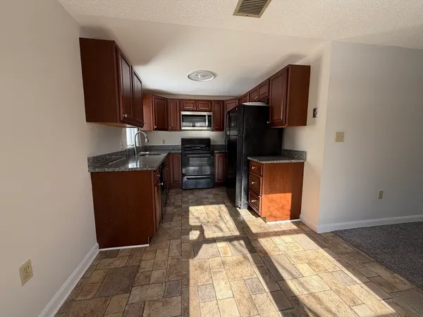 a kitchen with stainless steel appliances granite countertop a refrigerator a stove and a sink