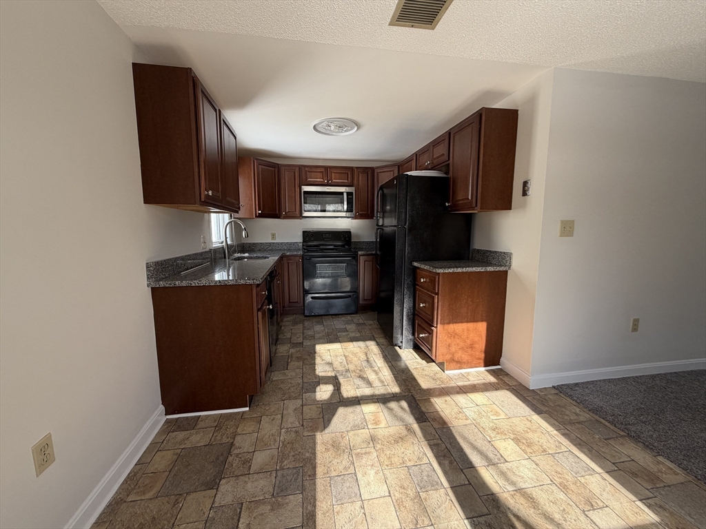 213 Victoria Heights Road, Unit 213 Boston, MA 02136 - Photo 4 of 18 a kitchen with stainless steel appliances granite countertop a refrigerator a stove and a sink