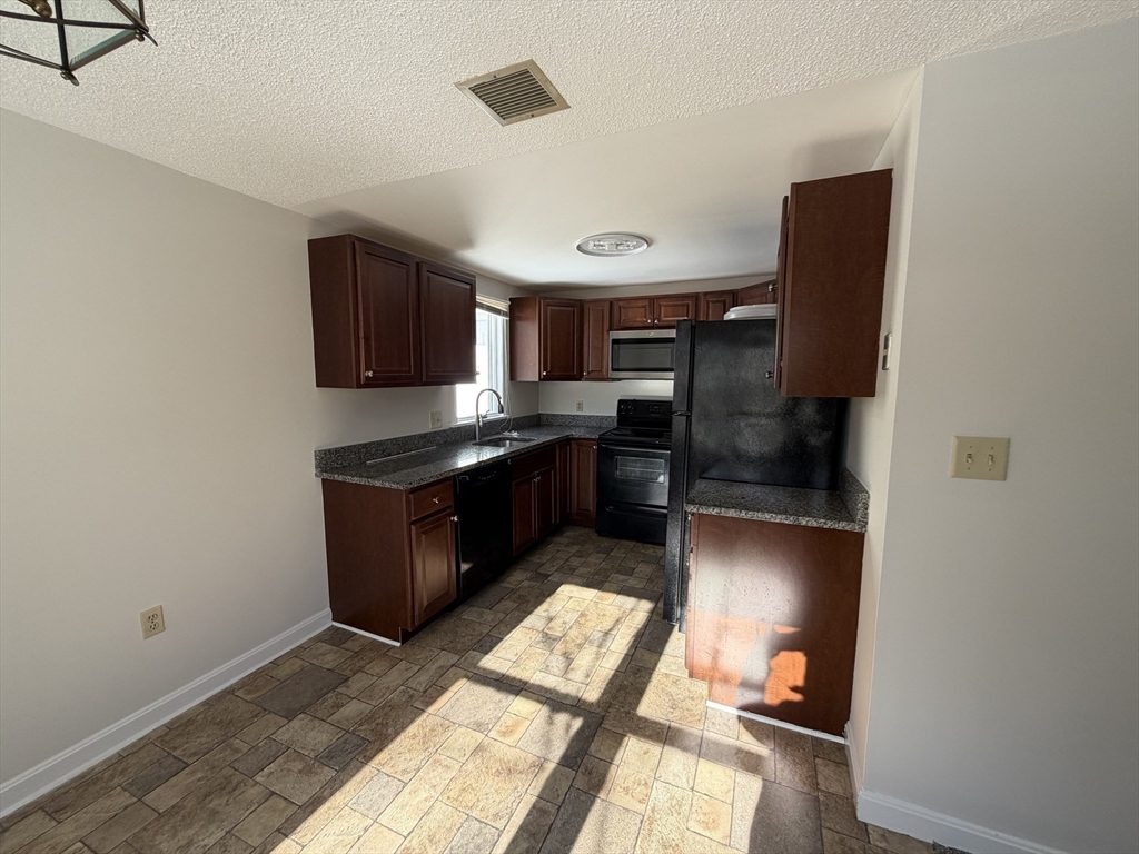 213 Victoria Heights Road, Unit 213 Boston, MA 02136 - Photo 5 of 18 a kitchen with stainless steel appliances granite countertop a refrigerator and a stove top oven