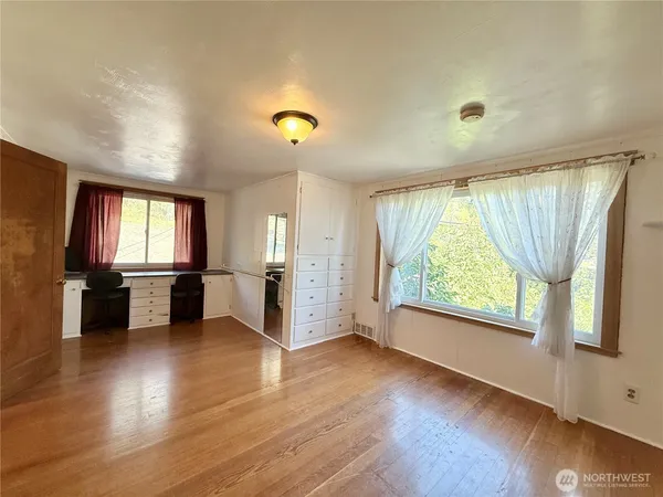 an empty room with wooden floor and windows