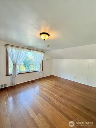 a view of a livingroom with wooden floor and kitchen space