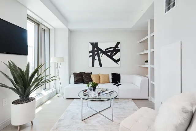 a living room with furniture a flat screen tv and a potted plant