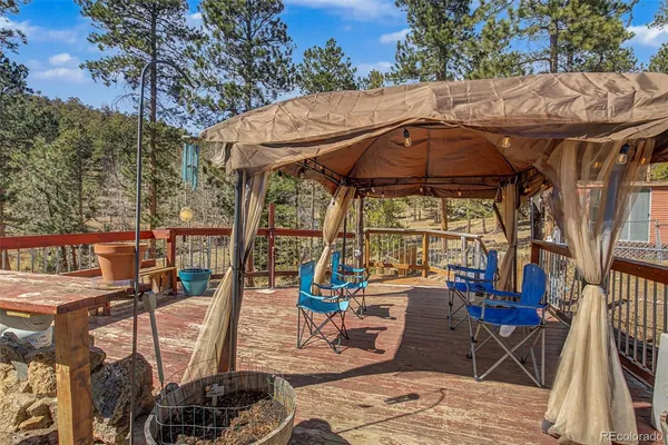 a view of a patio with table and chairs under an umbrella with a barbeque