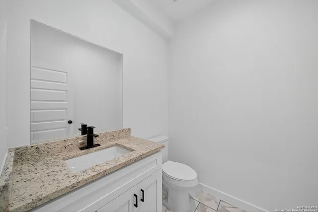 a bathroom with a granite countertop sink toilet and vanity
