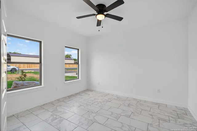 an empty room with windows and fan