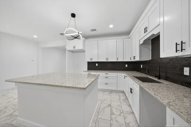 a kitchen with granite countertop a sink a stove and cabinets