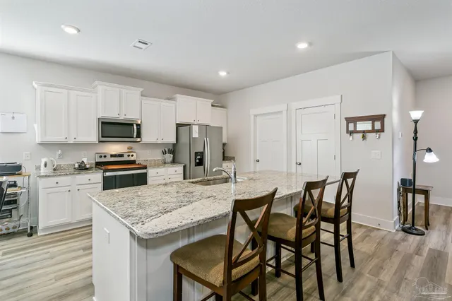 a kitchen with granite countertop white cabinets and stainless steel appliances