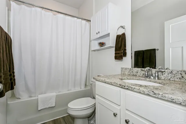 a bathroom with a granite countertop sink and a mirror with toilet