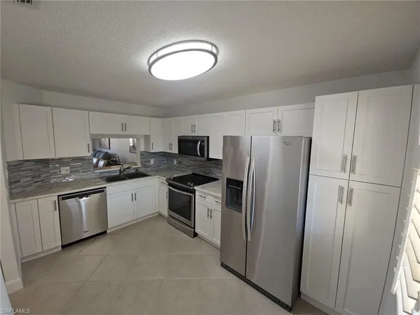 a kitchen with granite countertop stainless steel appliances a refrigerator a stove a sink and a refrigerator