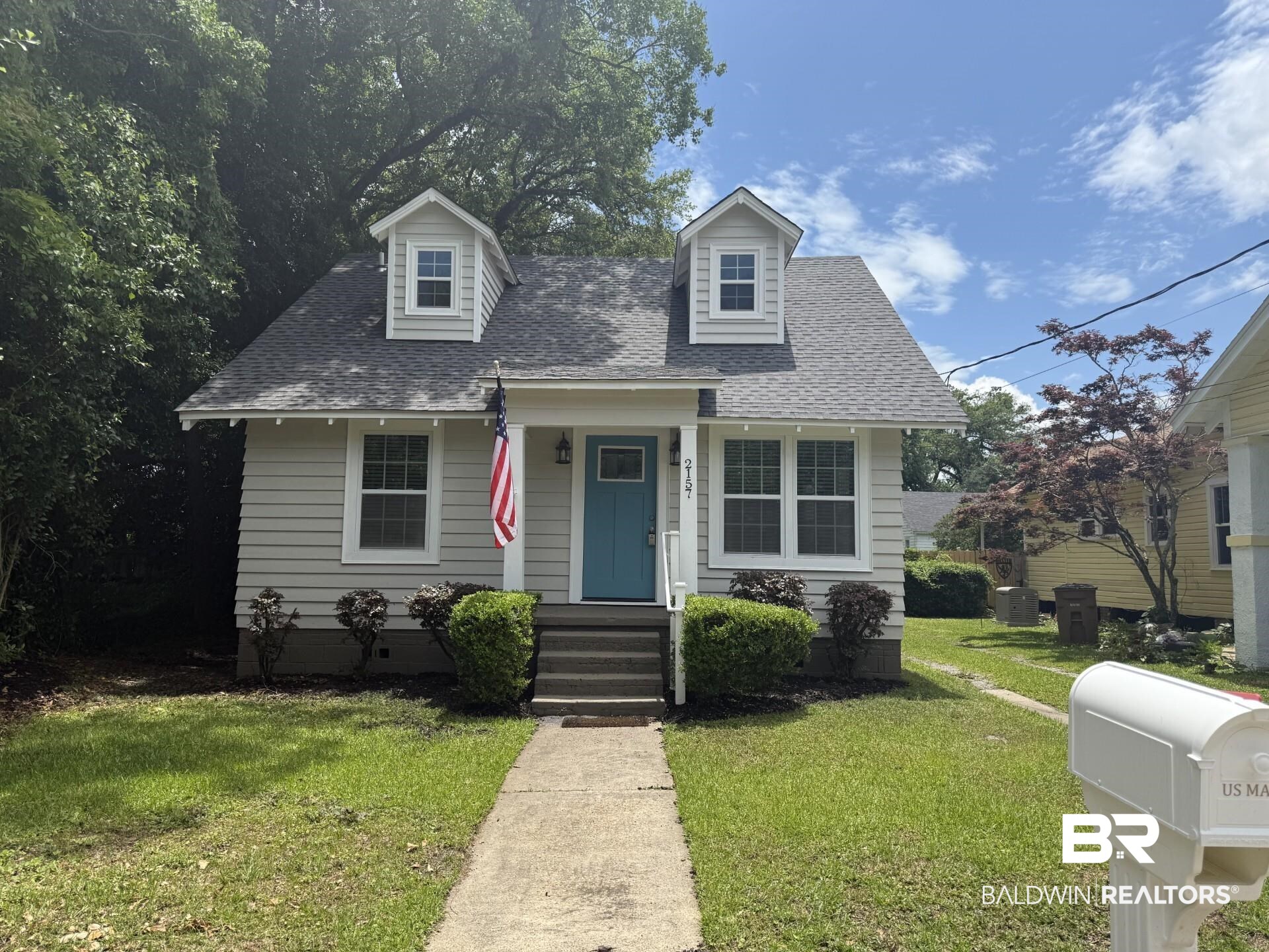 New england style home with a shingled roof and a front yard