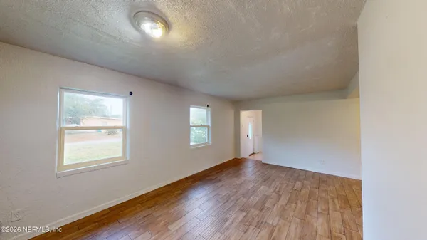 an empty room with wooden floor and windows