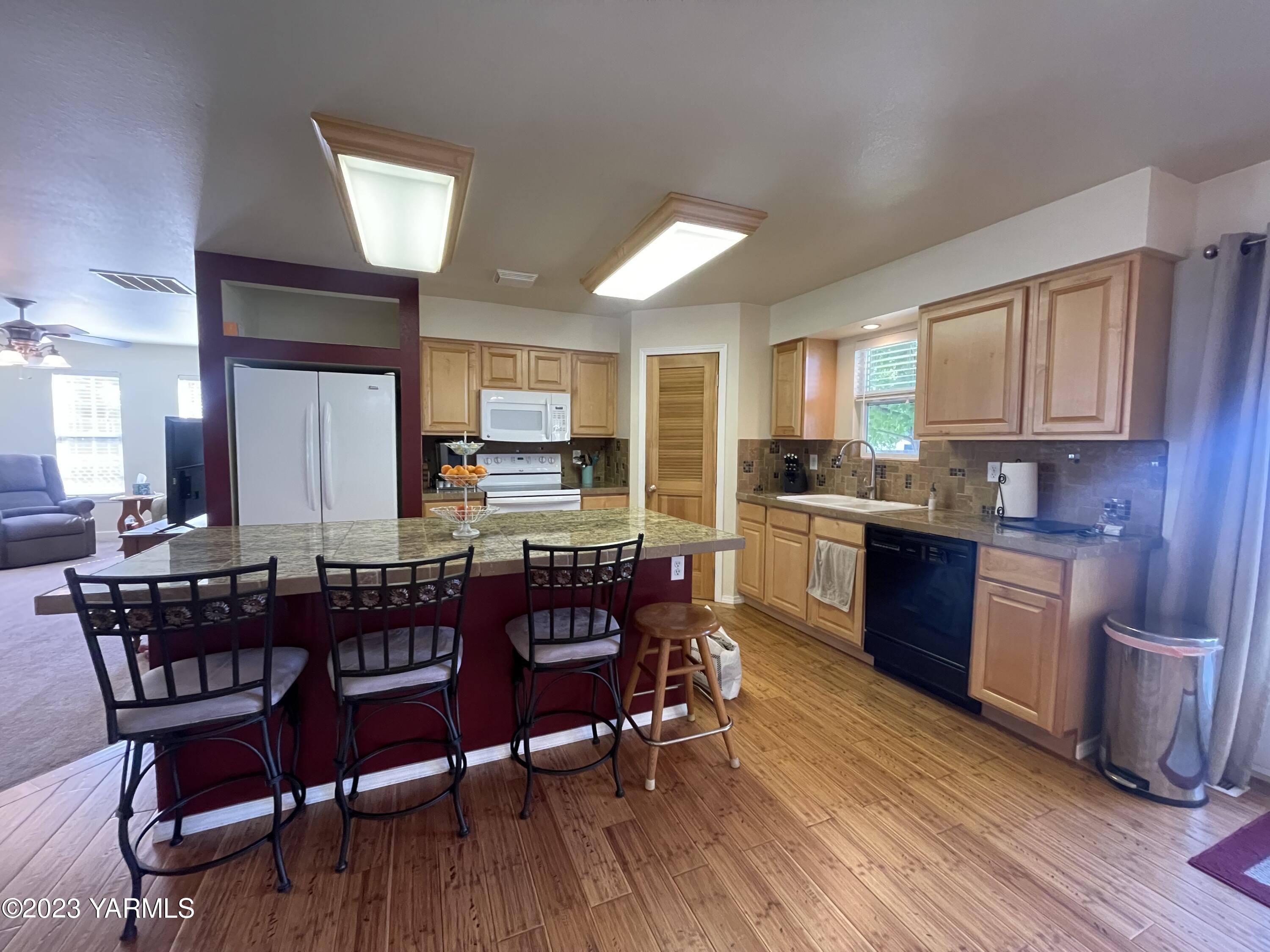 707 Larson Street Grandview, WA 98930 - Photo 3 of 16 a kitchen with stainless steel appliances granite countertop a dining table chairs refrigerator and microwave