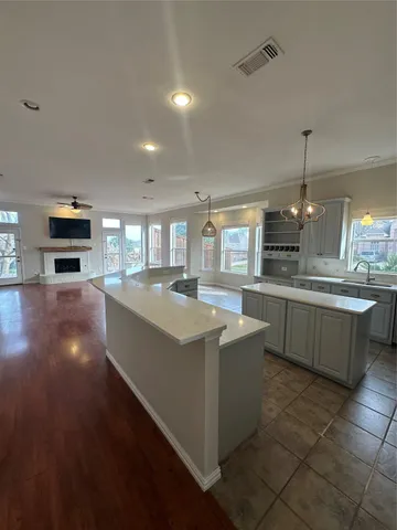 a kitchen with kitchen island granite countertop a stove top oven a sink a counter space and cabinets