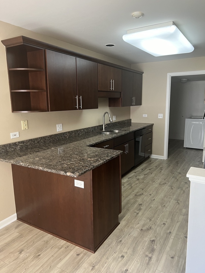 945 Huntington Drive, Unit 945 Elk Grove Village, IL 60007 - Photo 2 of 9 a kitchen with stainless steel appliances granite countertop a stove a sink and a microwave