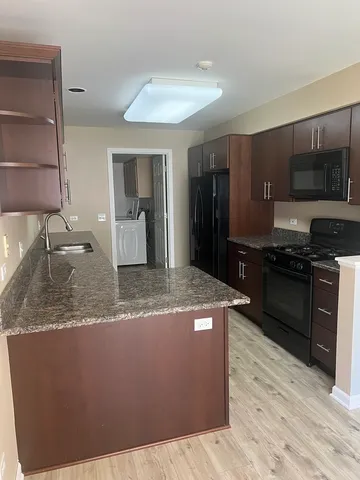 a kitchen with kitchen island granite countertop a sink cabinets and stainless steel appliances