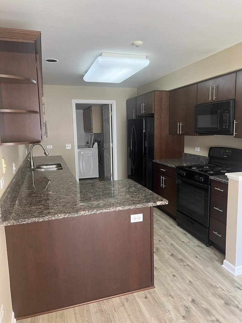 945 Huntington Drive, Unit 945 Elk Grove Village, IL 60007 - Photo 3 of 9 a kitchen with kitchen island granite countertop a sink cabinets and stainless steel appliances