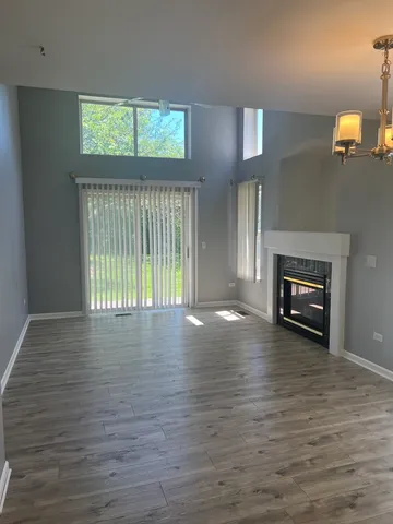 an empty room with wooden floor fireplace and windows