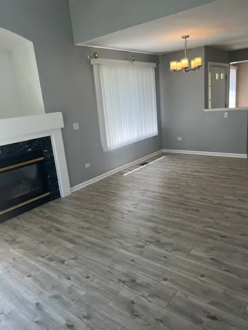an empty room with wooden floor fireplace and windows