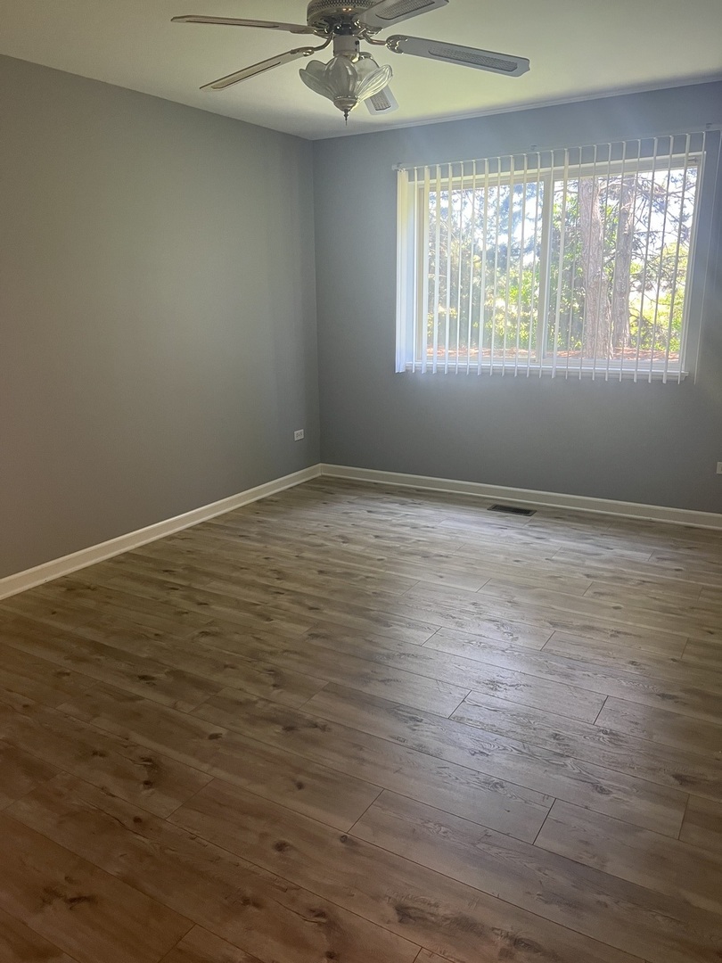945 Huntington Drive, Unit 945 Elk Grove Village, IL 60007 - Photo 6 of 9 an empty room with wooden floor and windows