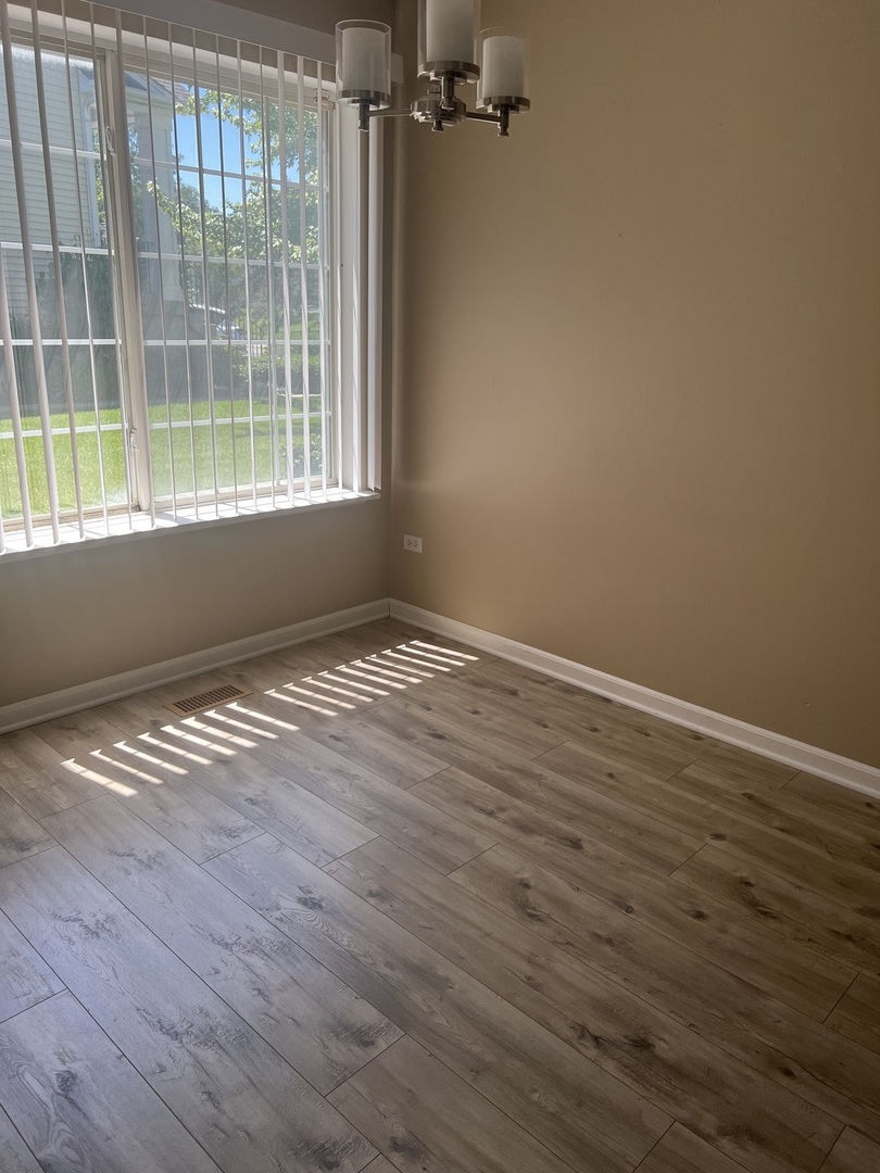 945 Huntington Drive, Unit 945 Elk Grove Village, IL 60007 - Photo 7 of 9 a view of empty room with wooden floor and fan