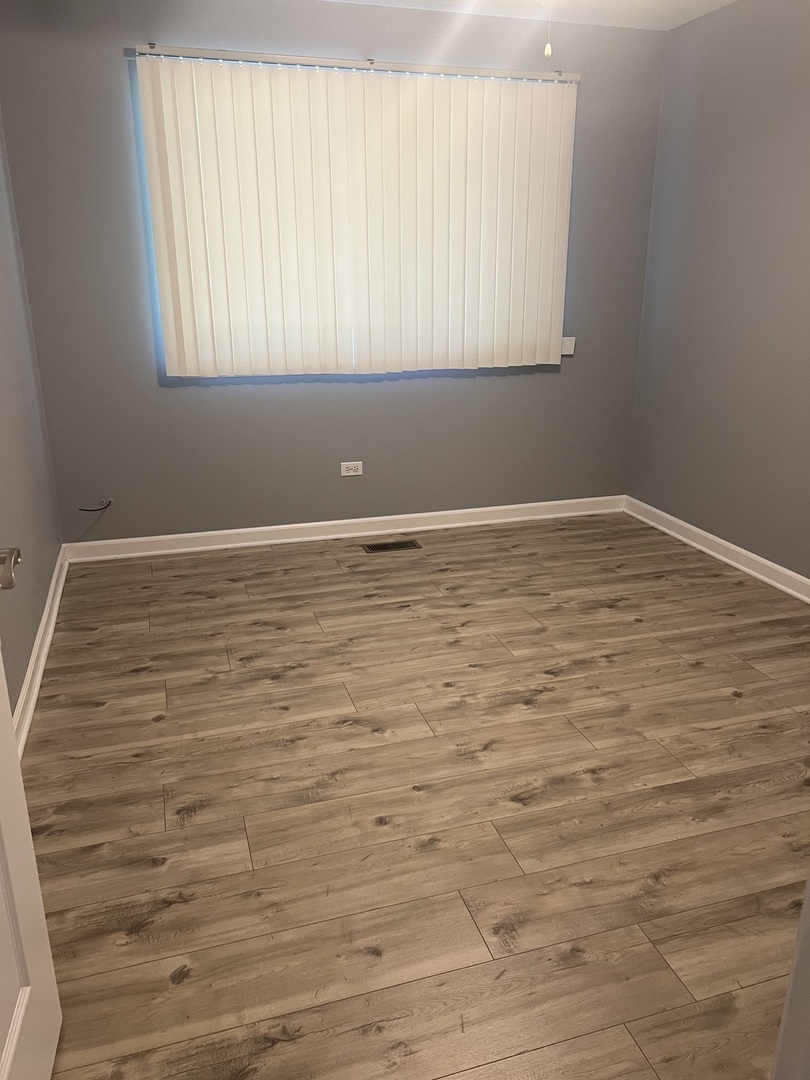 945 Huntington Drive, Unit 945 Elk Grove Village, IL 60007 - Photo 9 of 9 a view of an empty room with wooden floor and a window