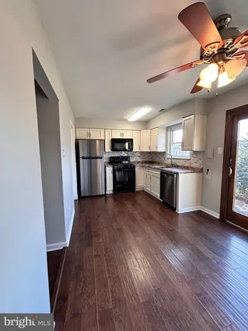 a kitchen with stainless steel appliances granite countertop a refrigerator a stove top oven a sink dishwasher and wooden floor