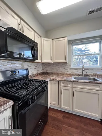 a kitchen with granite countertop a sink cabinets and stainless steel appliances