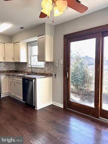 a kitchen with granite countertop a stove a sink and white cabinets with wooden floor next to windows