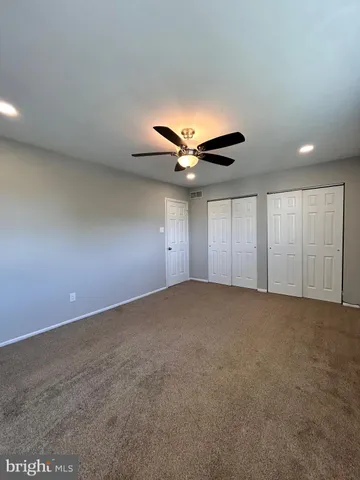 an empty room with a ceiling fan and window