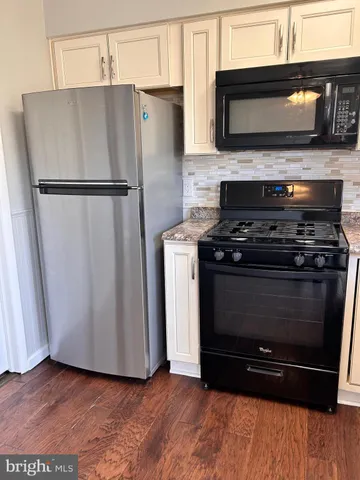 a kitchen with granite countertop a refrigerator stove and microwave